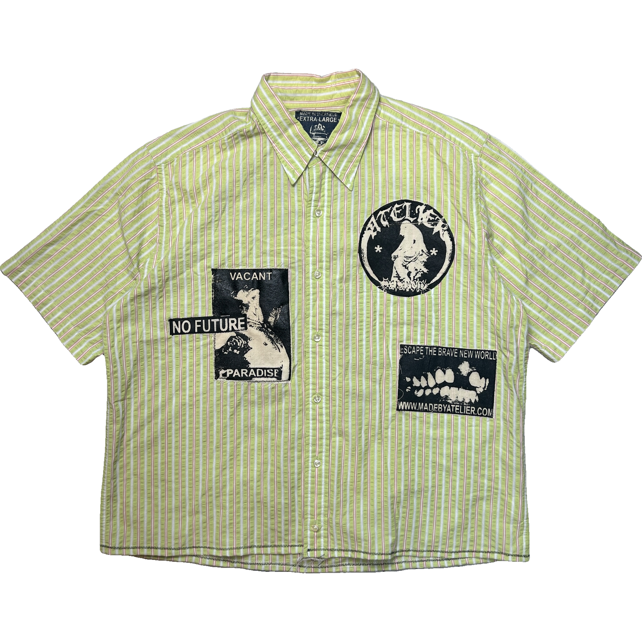 A short-sleeve button-up shirt with vertical light green and white stripes, featuring black graphic patches on the front. The patches include a circular patch with a reaper and the text 'paranoid' on the left chest, a rectangular patch reading 'VACANT NO FUTURE PPARADISE' on the right chest, and another rectangular patch with a skull and text on the lower right front.
